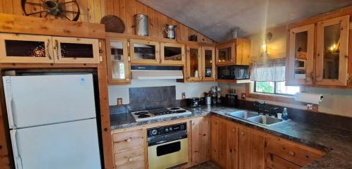 Cozy wooden kitchen with modern appliances, including a fridge, stove, and sink, surrounded by rustic decor.